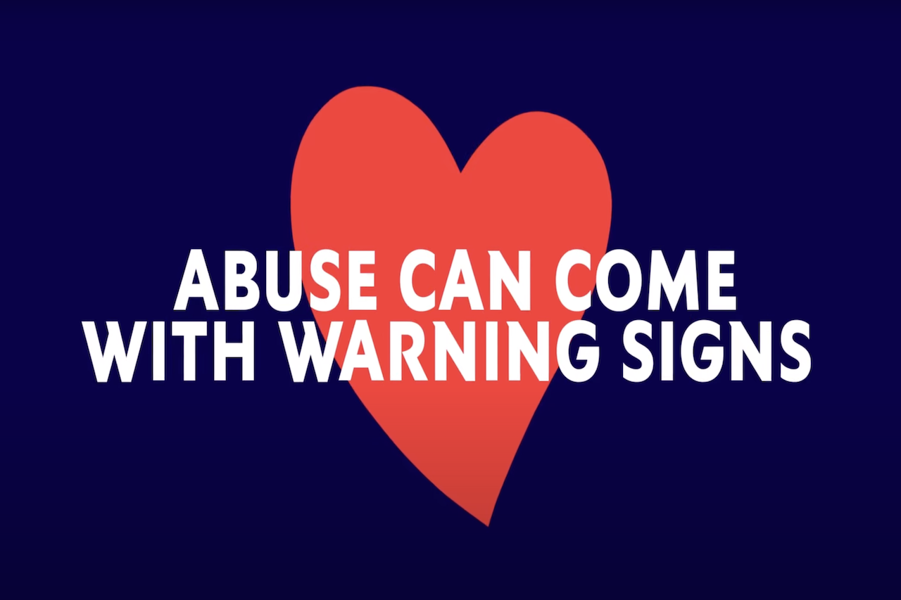Red heart on a navy blue background with text that reads "abuse can come with warning signs"
