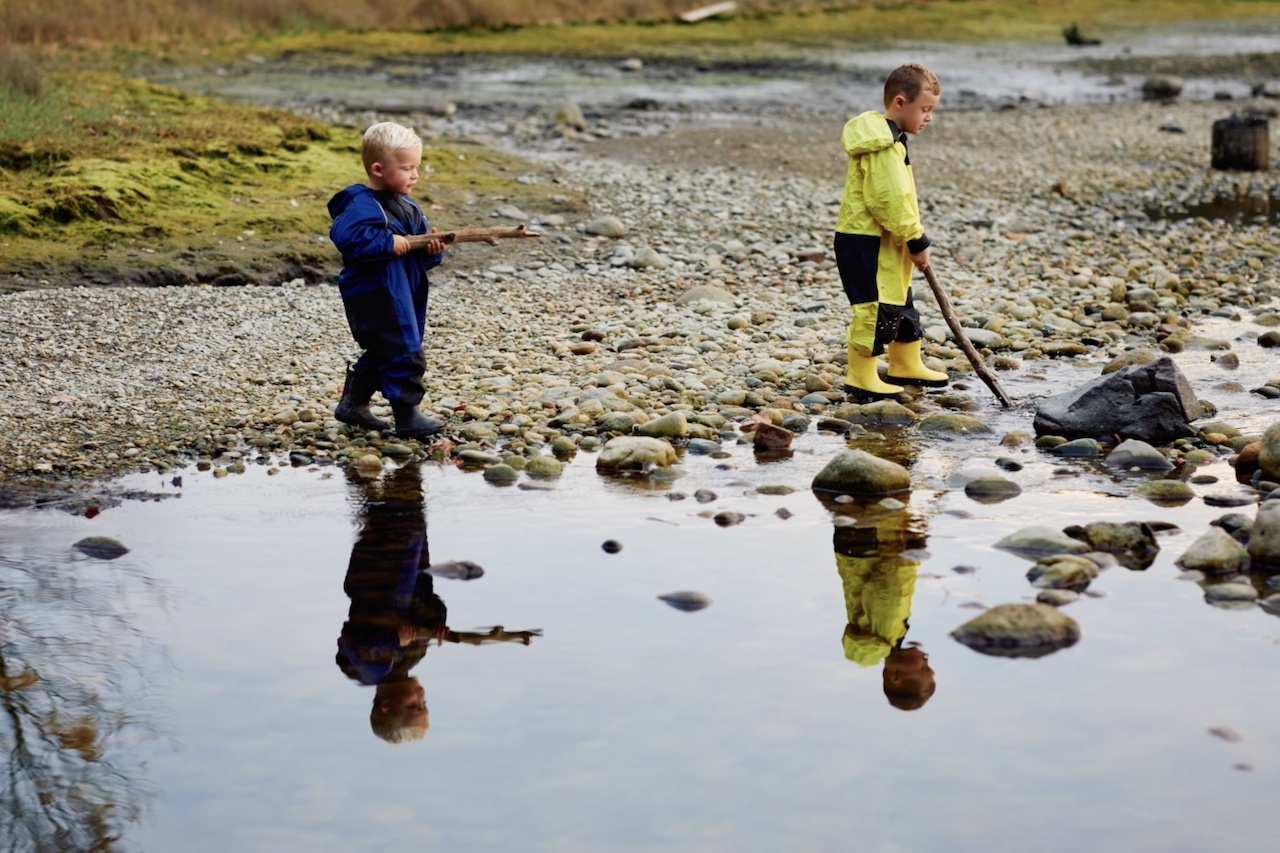 Two children playing near a stoney creek, both wearing Stonz outdoor apparel 